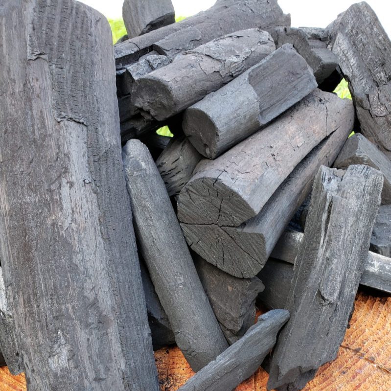Pile of premium JURK Charcoal spread out on a log base
